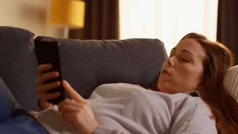 Woman-Lying-On-Sofa-At-Home-Fed-Up-And-Bored-With-Time-Wasted-Using-Mobile-Phone-To-Check-Social-Media-Message-And-Scroll-Online-1